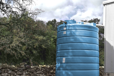 Wasserlagertank im Schatten neben einer Lagerhalle